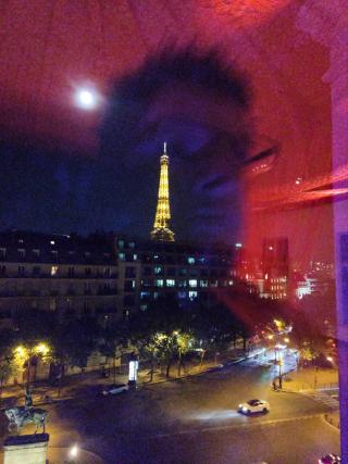 A picture of myself reflecting on a window glass. We can see the eiffel tower in the background