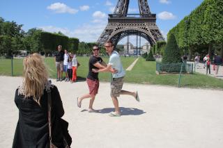 Two tourist being taken in picture in front of the eiffel tower