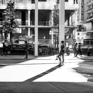 une femme qui attend a l'ombre d'un poteaux pour aller au cinéma