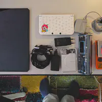Desk with multiple electronic devices such as computer, batteries, and gameboy