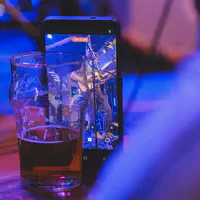 A phone left against a beer glass to record the concert. Jean-Loup is playing guitar is visible on the screen