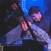 Makoto is all hands in the piano strings to fix microphone placement that interfered with the sound.